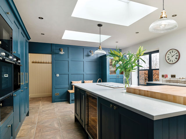 glass dome pendants and matching wall lights over a kitchen island in a rear extension with blue cabinets