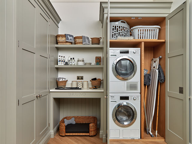 utility room with stacked washing machine and dryer pet basket and wood flooring