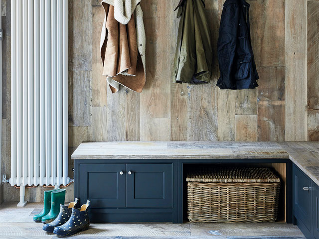 Modern utility room with lower blue cabinets and large wicker baskets and hanging jackets on coat rack