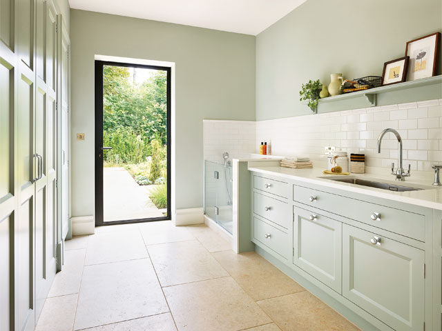 Bright utility room with stone flooring and full height glass door leading to garden