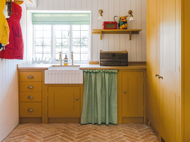 Bright yellow kitchen add on with green curtain and white sink with coat rack