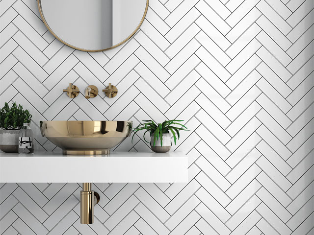 innovative bathroom with metallic basin and gold taps with white herringbone tile