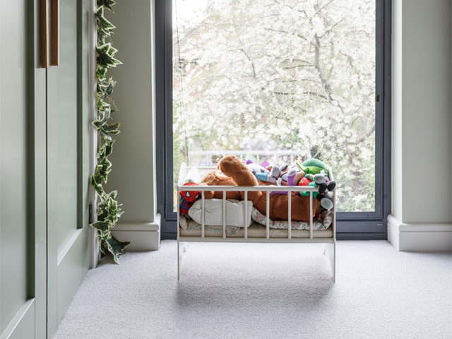 teddy bear in crib by large window green cupboard door