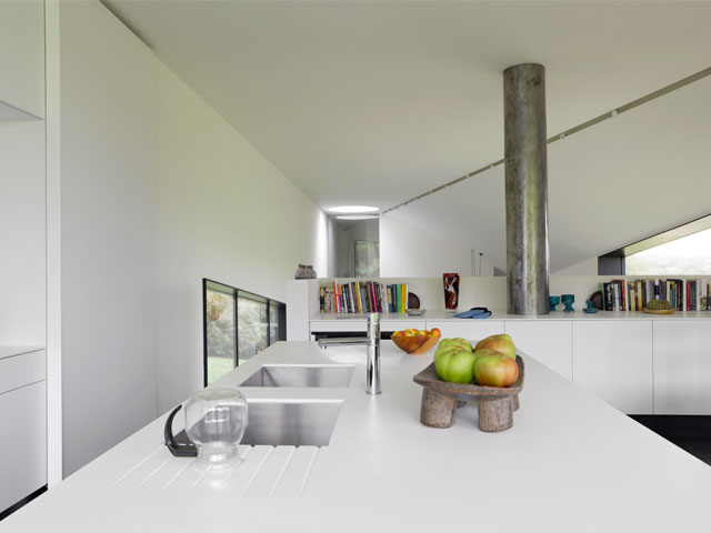 White open-plan living room and kitchen connected by a slope and stairs with metallic extraction flue