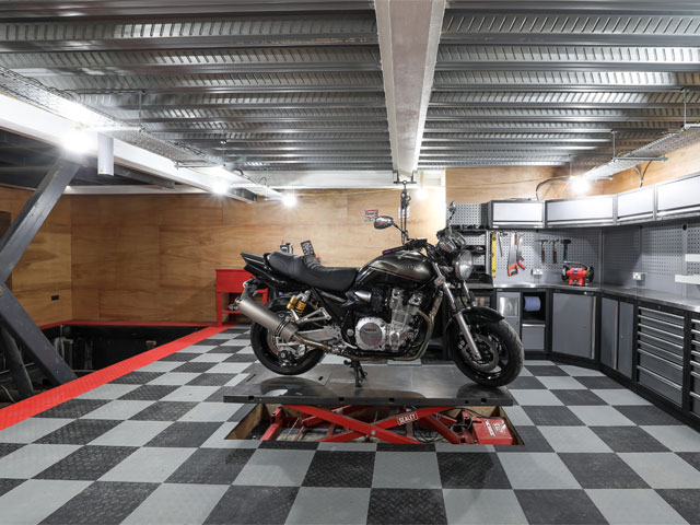 raised motorbike in contemporary basement workshop industrial tiles car lift Grand Designs: the streets