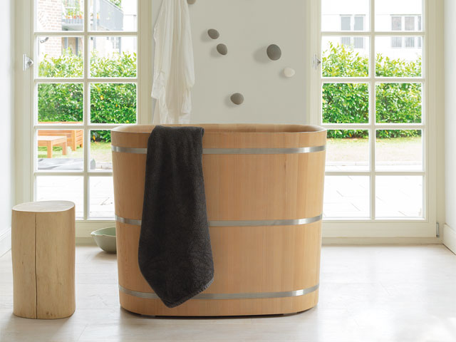 wooden bathtub with black towel full height glass doors