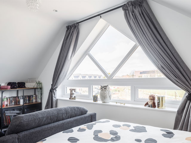 Large triangular bedroom window with small grey sofa