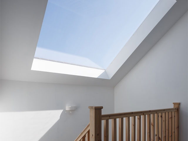 large architectural skylight wooden banister sunny day white walls