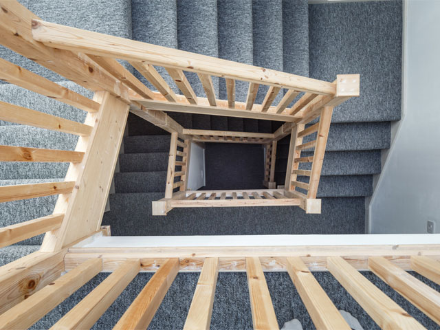 Birds eye view of stairs wooden bannister blue carpet grand designs the streets