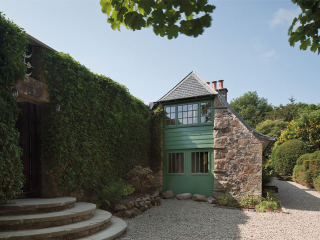 Large hedge with doorway entrance stone steps green fronted bothy gravel drive