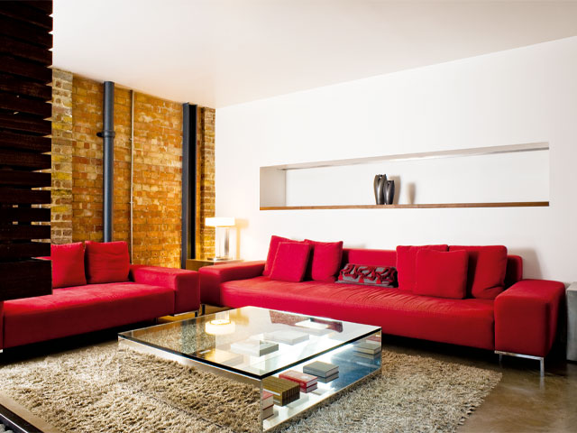 Minimal home interior white and exposed brick walls large red sofas glass coffee table wool rug