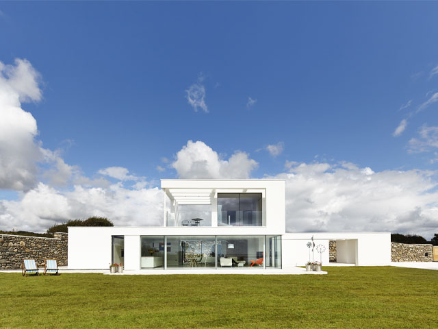 Ultramodern white contemporary home surrounded by glass blue sky modernist