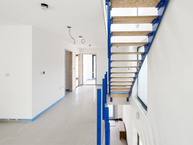 White hallway blue stairs electrical wires concrete floor