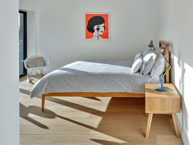 white bedroom blue bedcovers red artwork wooden bedside table with blue lamp