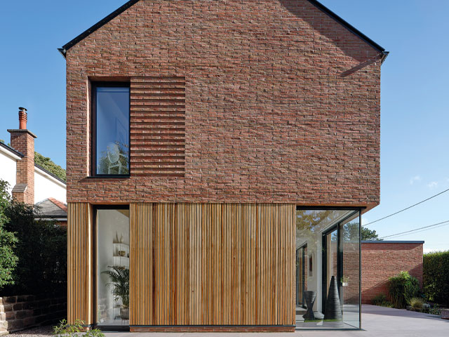 Home exterior of handmade bricks with timber cladding floor to ceiling glazing blue sky