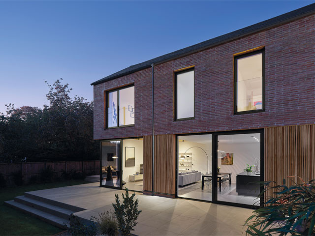 Contemporary home exterior at dusk timber cladding stone decking