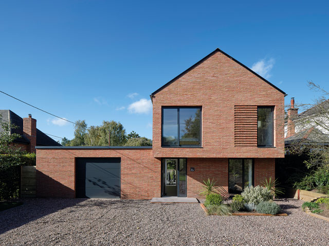 Modern contemporary home against blue sky with gravel driveway