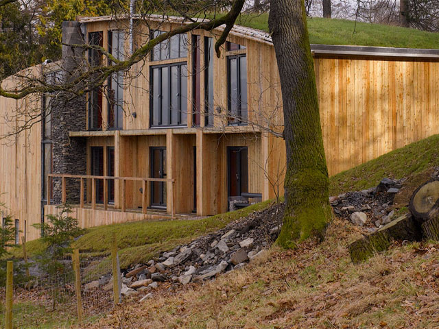 Grand Designs: Living in the country. Timber home large glazing in front of tree with stones