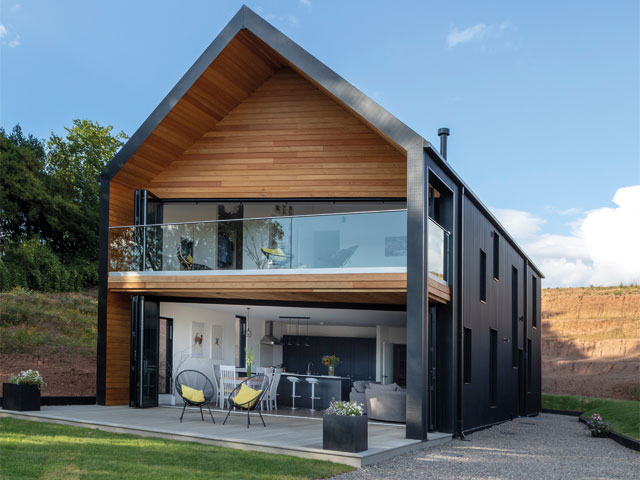 Timber and steel clad home exterior with balcony large glazed front windows