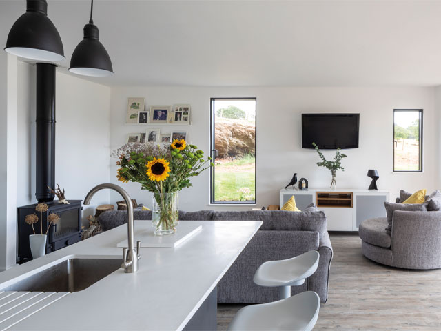 Grand Designs Leominster. Grey sofa matching circular love seat white barstools sunflowers large window