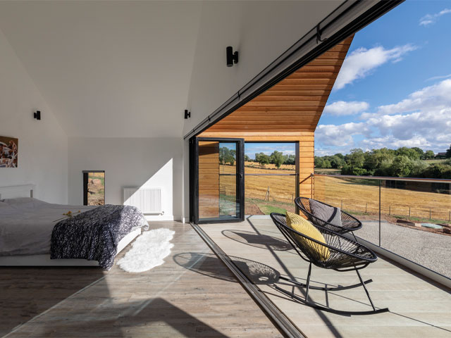 Bedroom wood flooring leading to large balcony retractable glass wall circular rocking outside seats