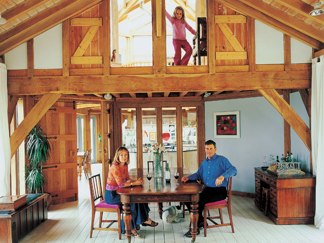 Grand Designs Rupert Upton. man woman sitting at wooden table child on mezzanine oak framed house