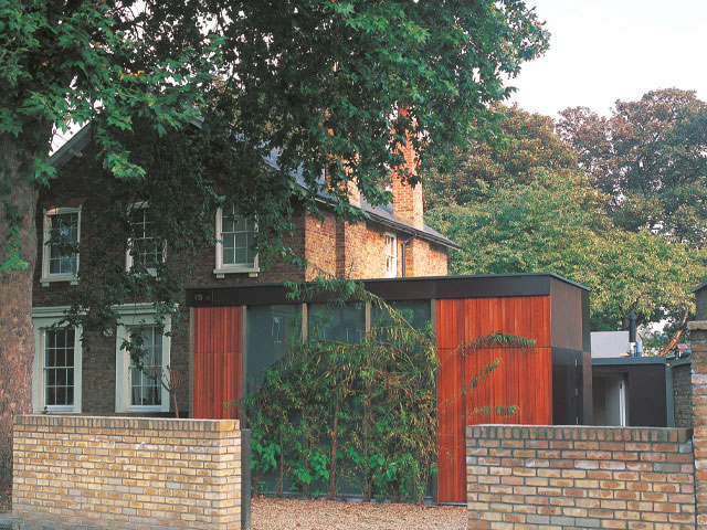 cedar clad home exterior gravel drive white window frames large oak tree light coloured brick wall