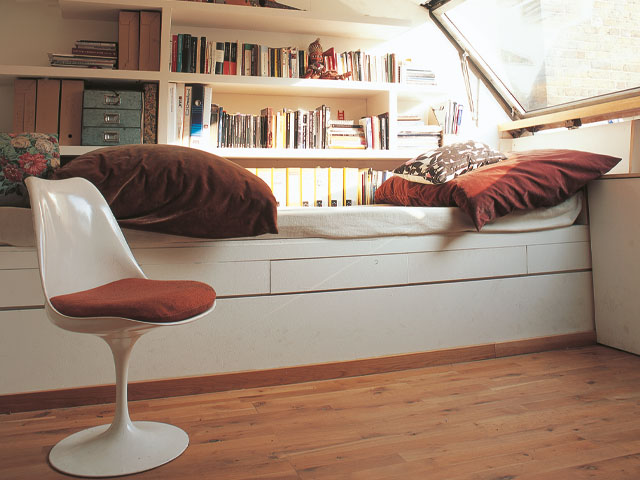 fitted single bed bookshelf red cushions white 70's chair wooden flooring