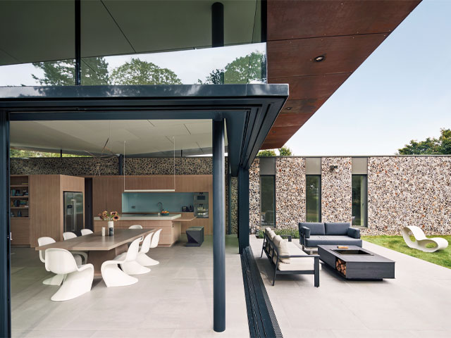 energy saving tips. large modern contemporary open plan kitchen diner retracted glass panels leading to garden stone clad walls