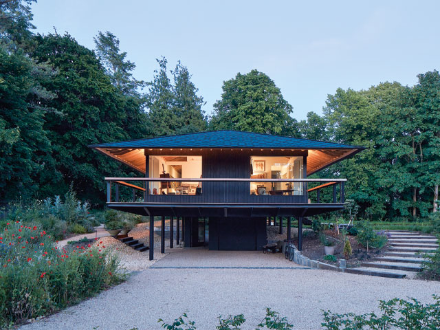 raised contemporary home exterior large eaves surrounding porch surrounded by woods