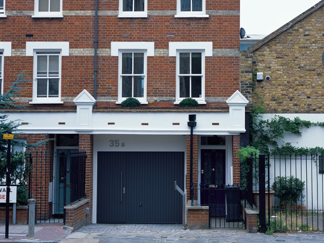 redbrick home exterior with blue garage door and blue front door white window frames