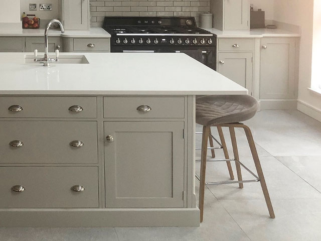 Beige cabinets on marble surfaced kitchen island large black hob cooker 