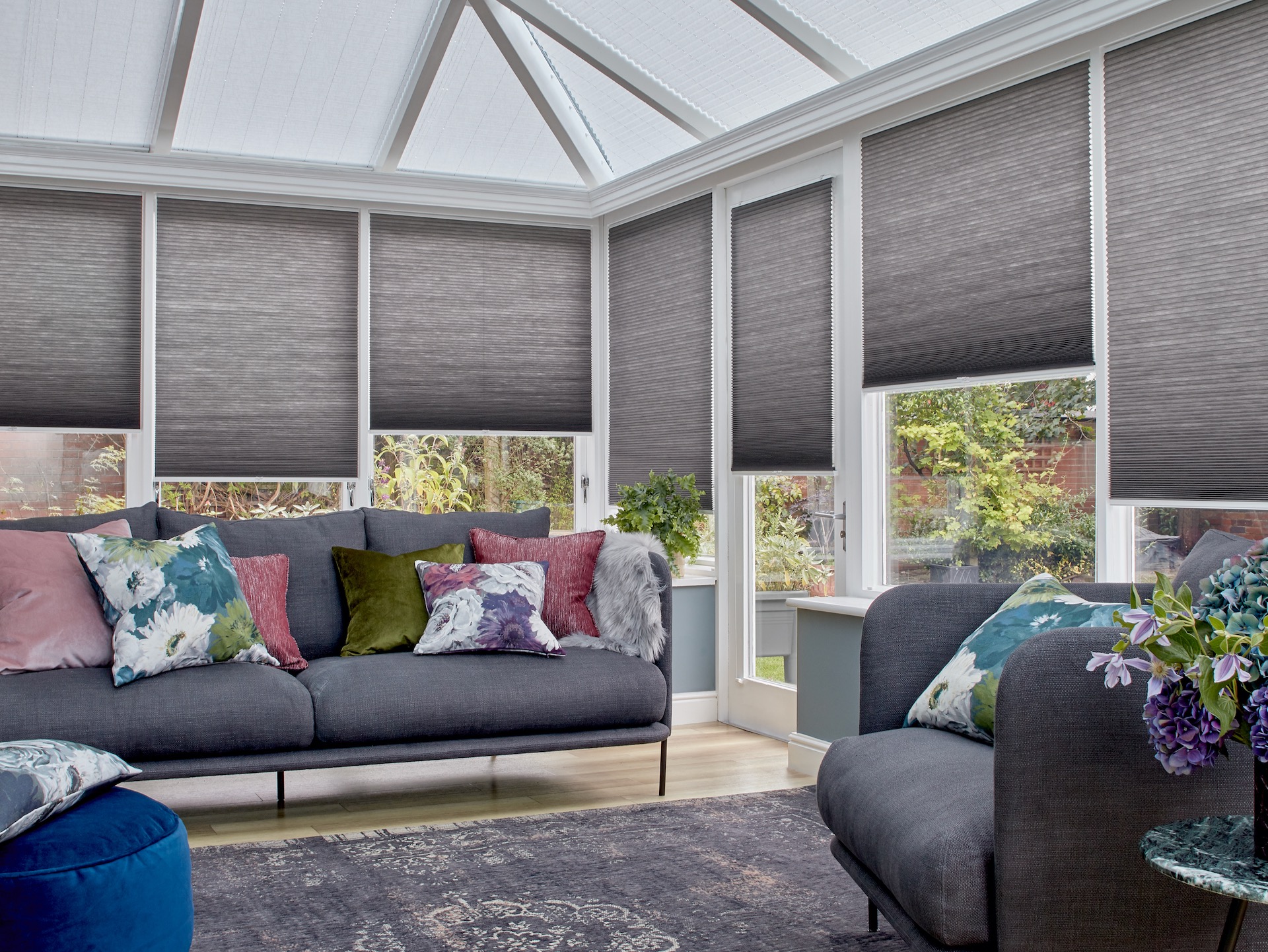 Conservatory with grey blinds, grey sofa and armchair 