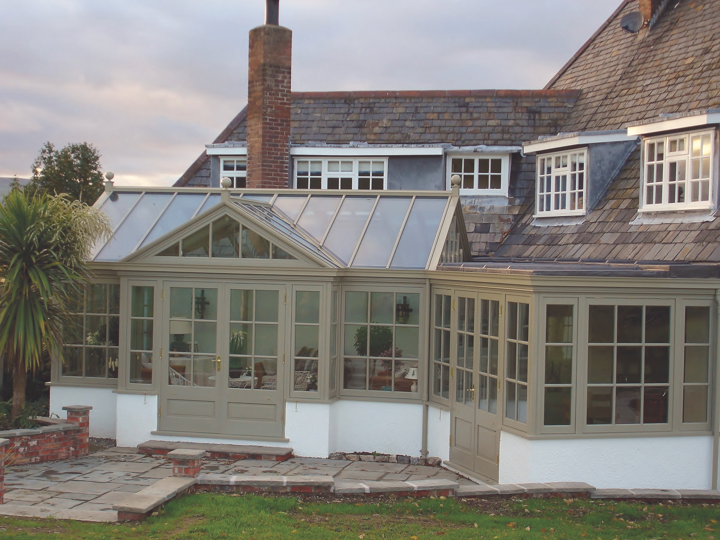 Wrap-around conservatory with double doors in sage green