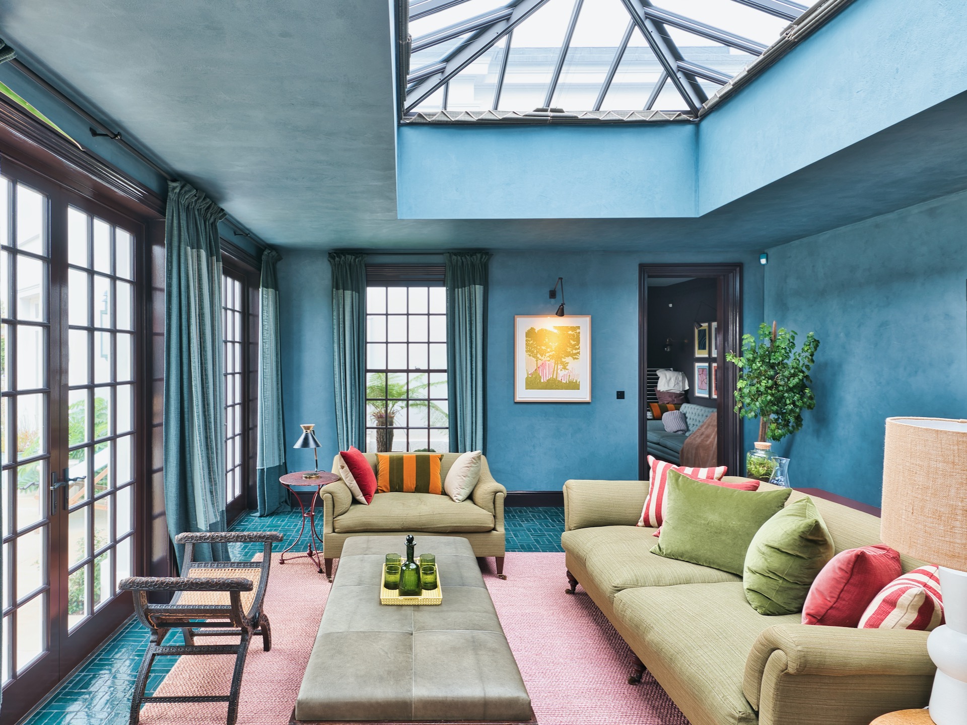 Conservatory sitting room with blue walls and green sofas