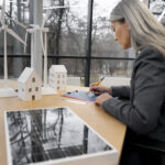 A woman looking at model of a building and making calculations