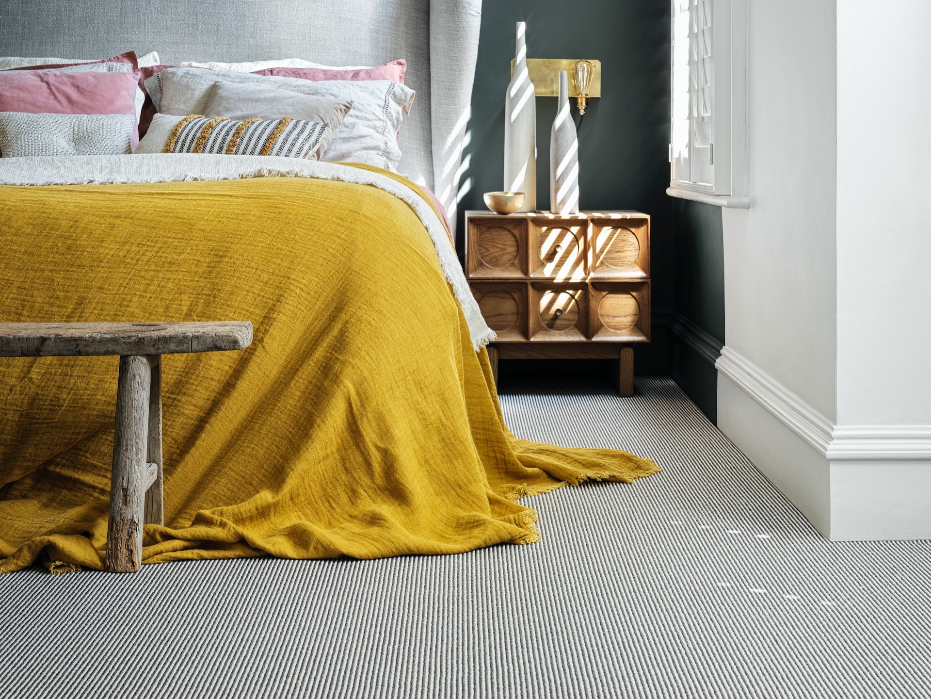 Finely striped carpet in bedroom with mustard bedspread