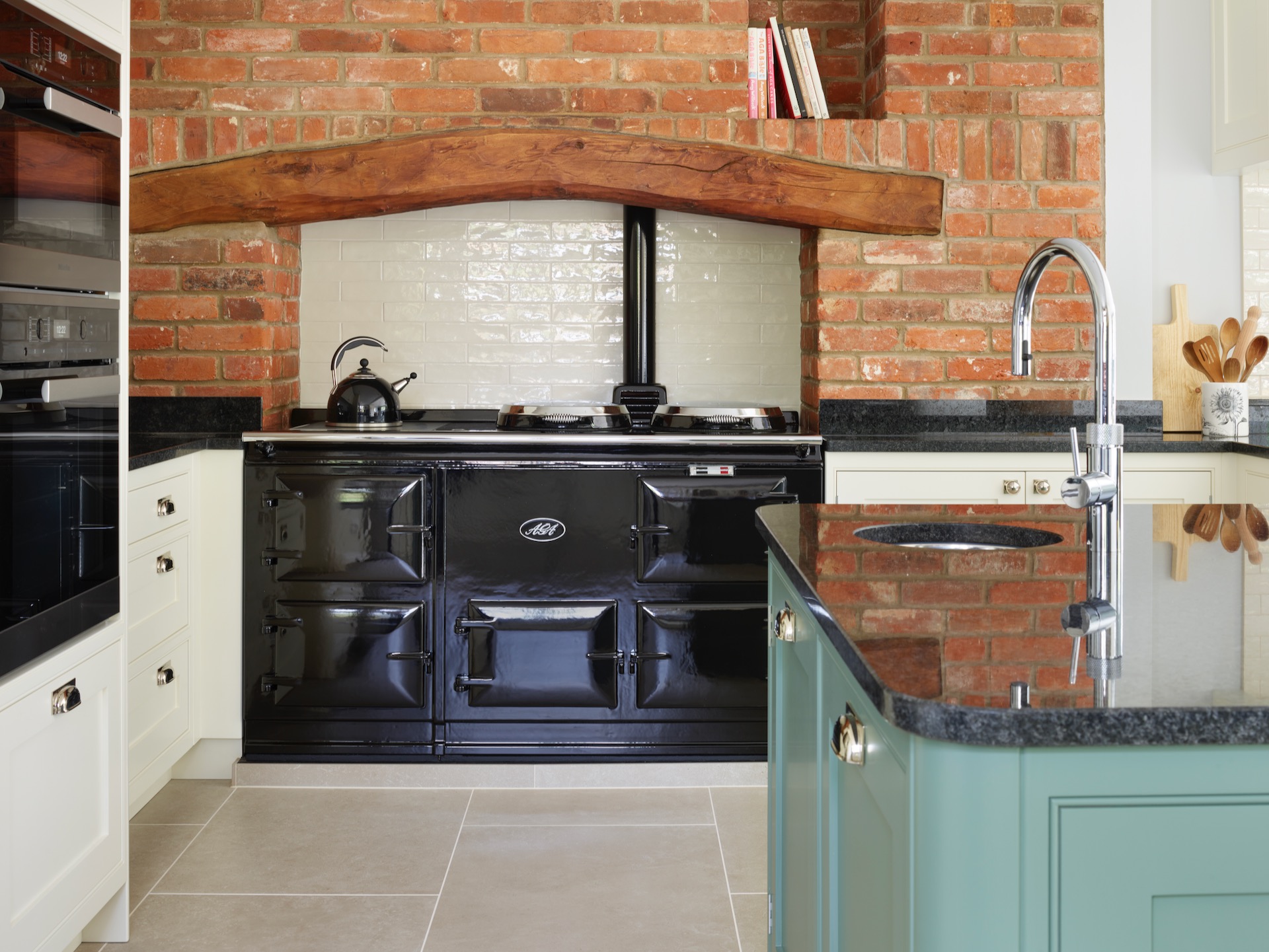 White and green kitchen with black aga in fireplace