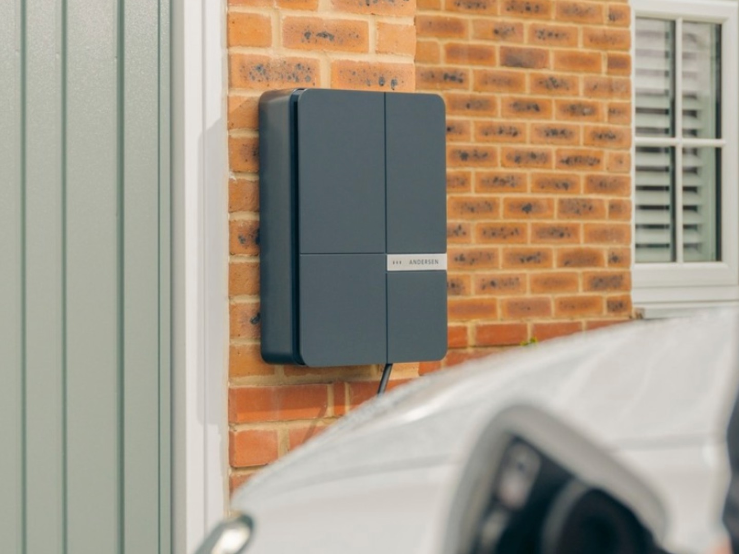 Grey Andersen EV charger on brick wall of house