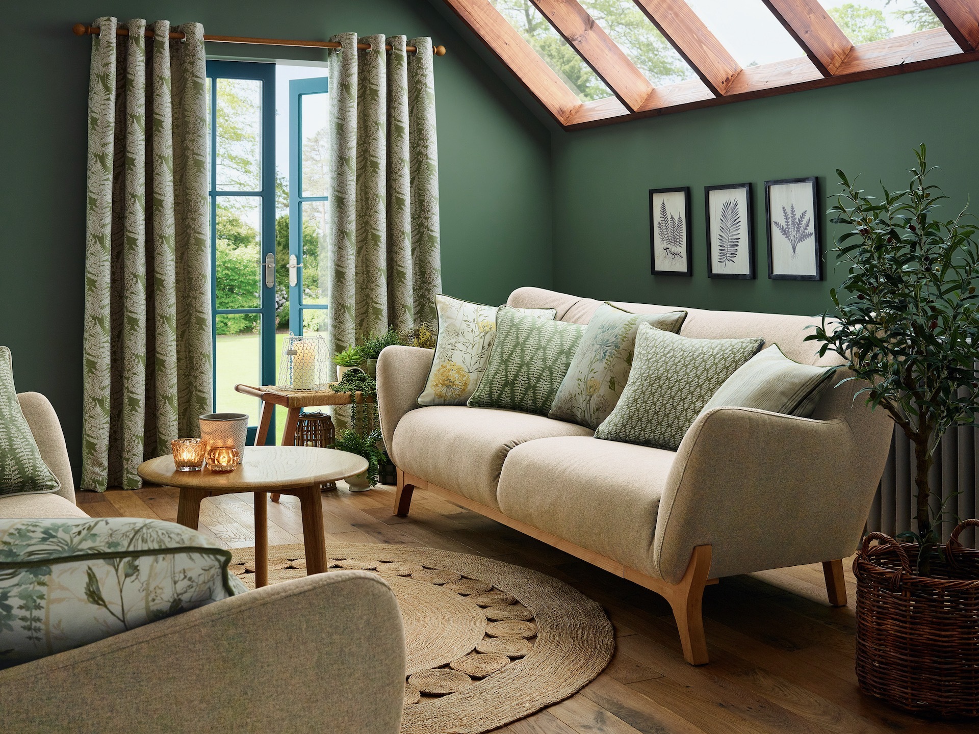 Garden room with green walls, cream sofa and botanical print curtains