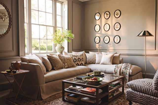 Corner luxury sofa in large window area in panelled living room with tiered coffee table