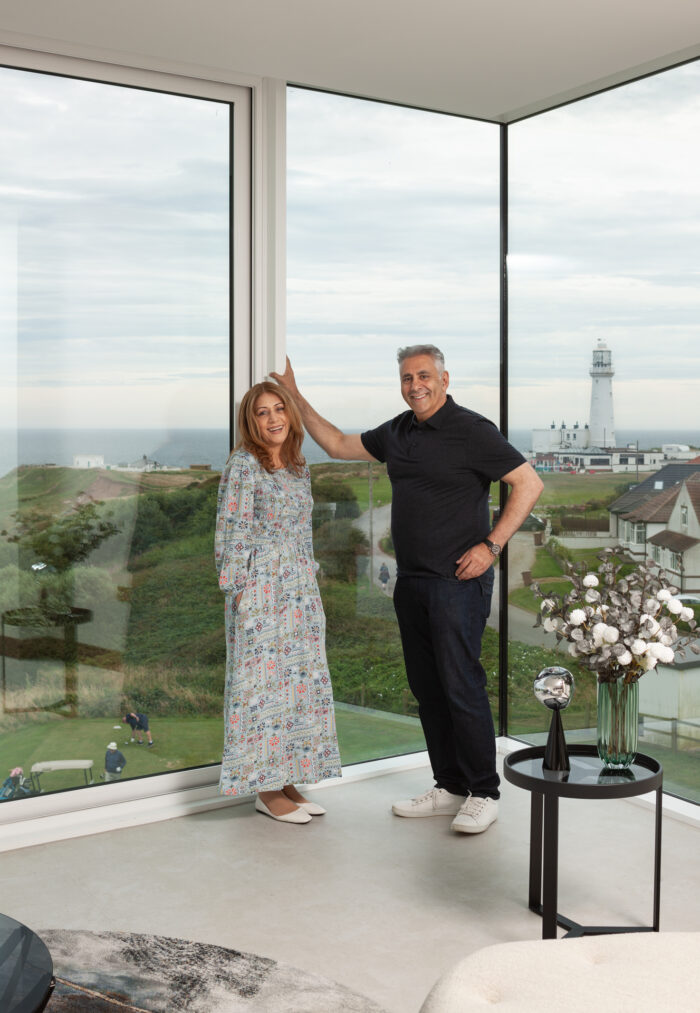 Homeowners Ferzana and Zahid in the living room, which has corner glazing providing panoramic views