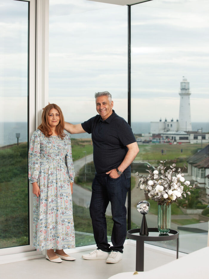 Homeowners Ferzana and Zahid in the living room, which has corner glazing providing panoramic views