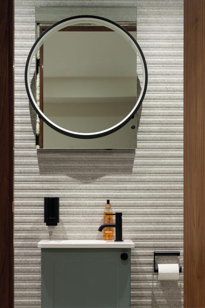 A panel of textured tiles from Porcelanosa features behind the vanity unit in one of the ground-floor guest room en suites