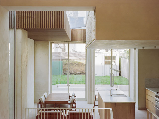Looking from staircase to open-plan kitchen with dining area and view through glazing to double doors