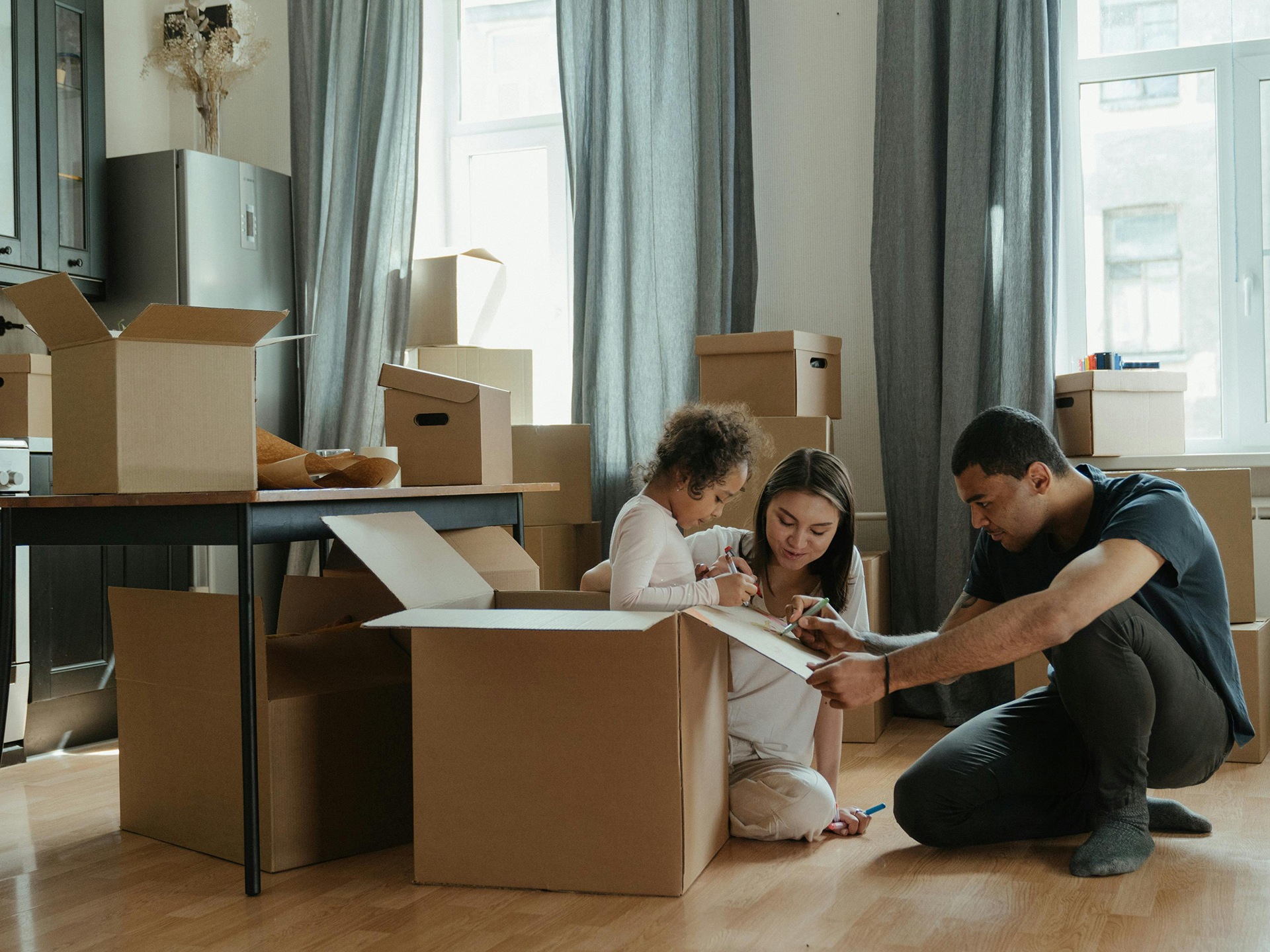 Parents and a young girl in a room surrounded by moving boxes