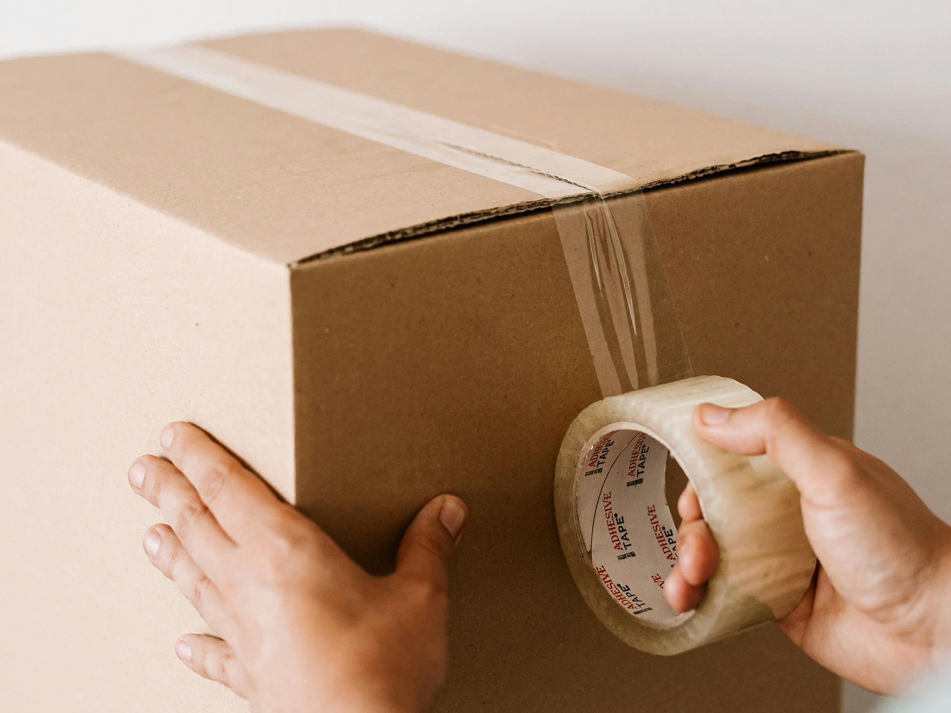 Someone taping up a cardboard box