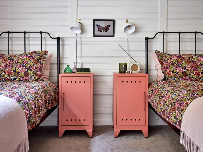 A pair of pink bedside cabinets between two beds