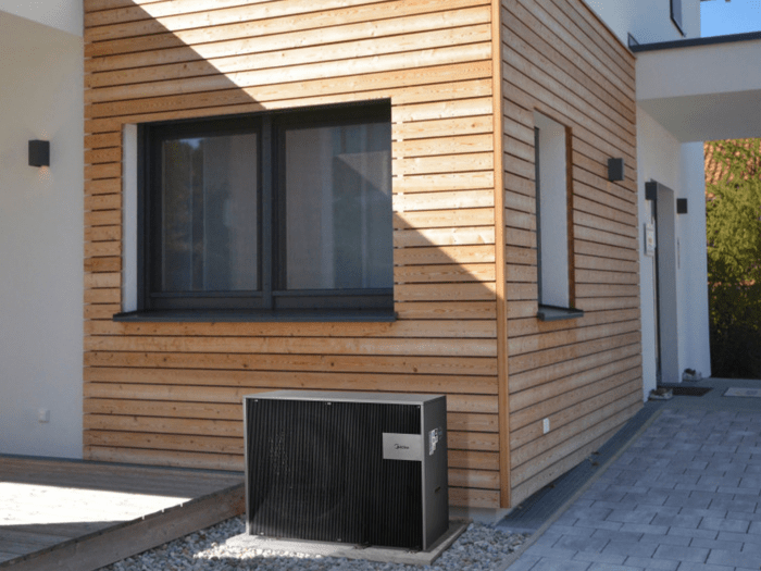 The external unit of an air-source heat pump outside a modern home