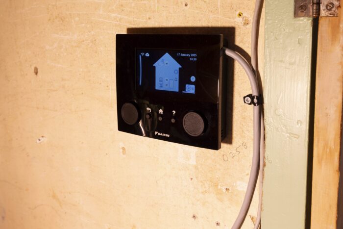 A large control panel with a picture of a house on screen, displaying indoor and outdoor temperatures and tank temperature and pressure